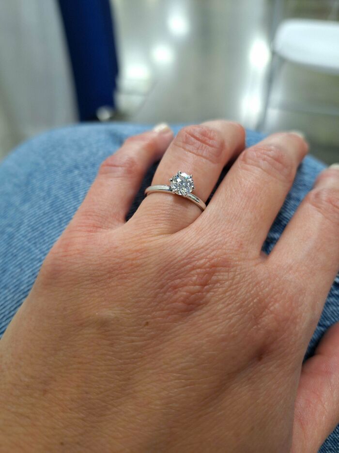 Hand wearing an engagement ring, illustrating a funny wholesome anniversary surprise moment.