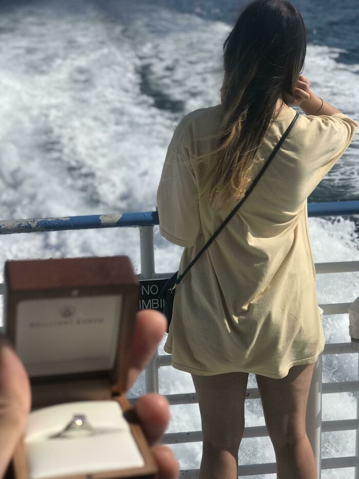 A woman on a boat glances at the sea while a hand presents a ring, symbolizing long-distance love.