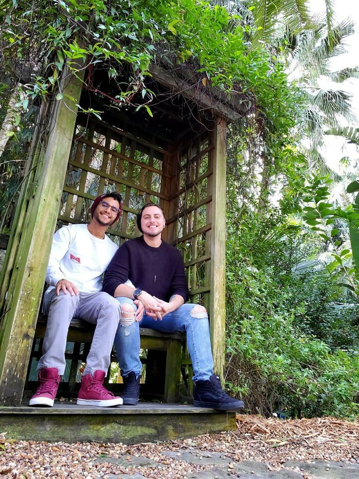 Two people sitting together in a cozy wooden gazebo surrounded by lush greenery, showcasing long-distance love.