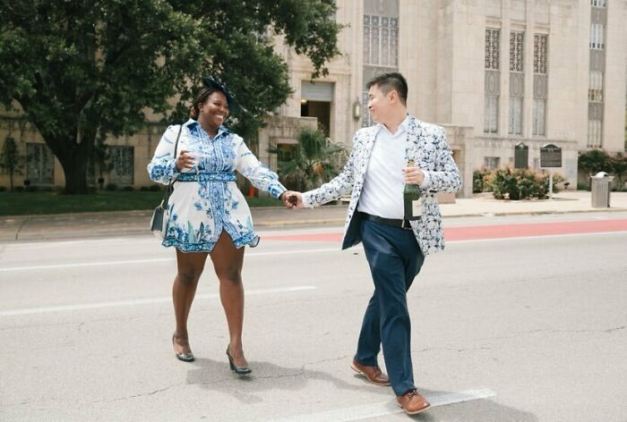 A joyful couple in stylish outfits holding hands, showcasing long-distance love triumphs on a sunny street.