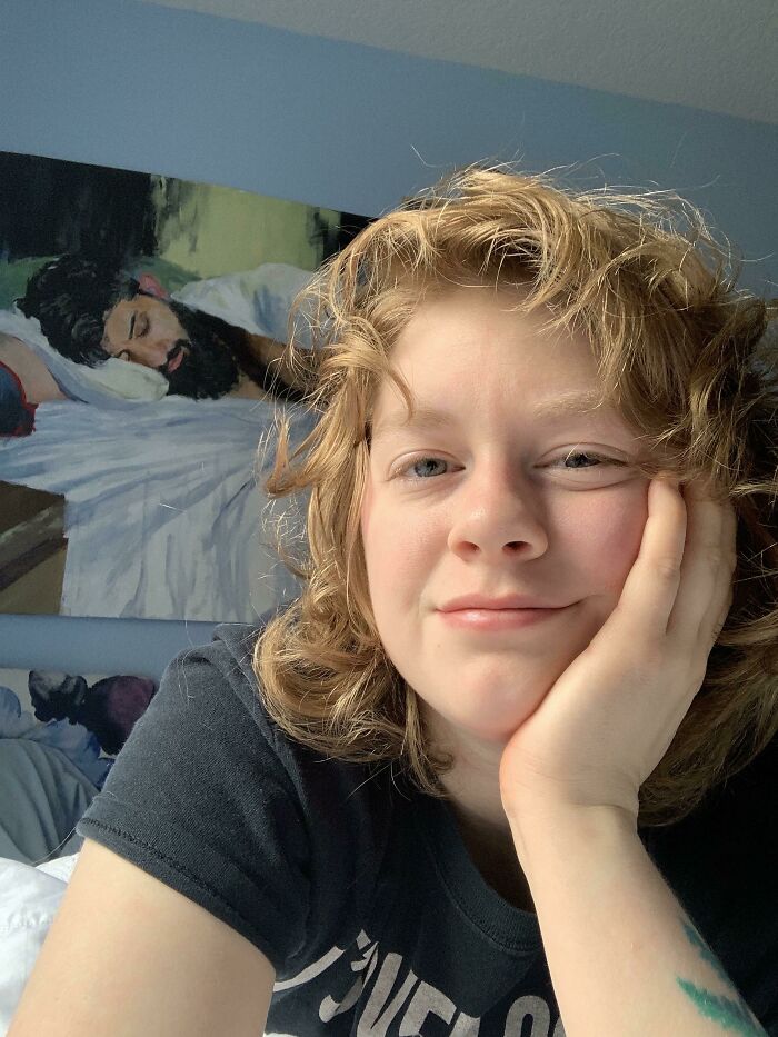 Smiling person relaxing at home with a painting in the background, symbolizing long-distance love.