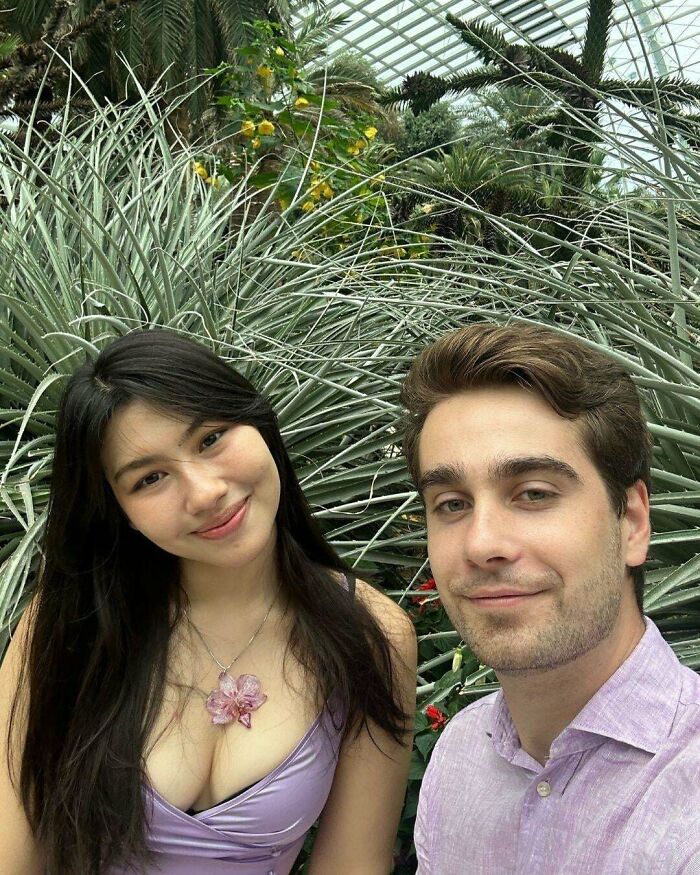 A couple smiling in a lush greenhouse, showcasing long-distance love.