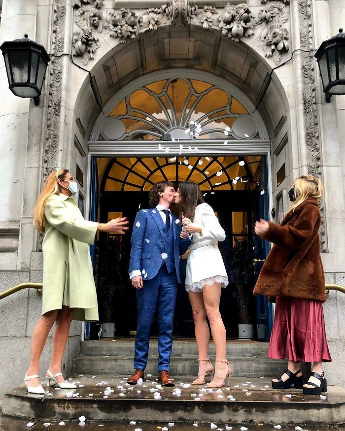 Couple kissing at their wedding with guests throwing confetti, celebrating long-distance love.