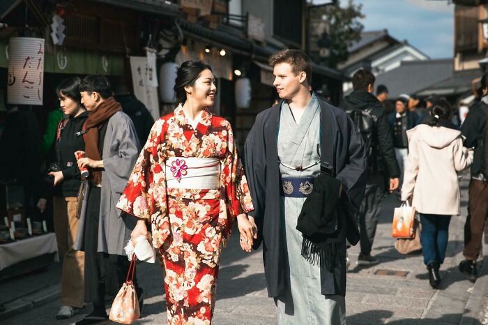 Couple in traditional attire holding hands, walking in a busy street, showcasing long-distance love.