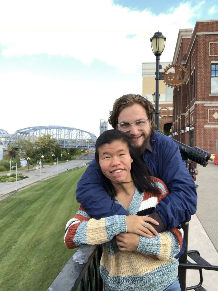 Couple embracing on a riverside walkway, symbolizing long-distance love conquering challenges.