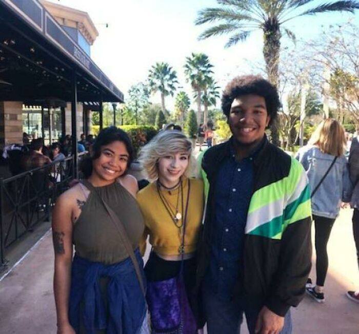 Three smiling friends posing together outdoors, radiating love and joy.