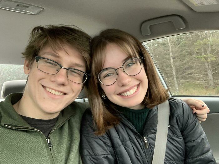 A happy couple in a car, smiling for a selfie, showcasing long-distance love.