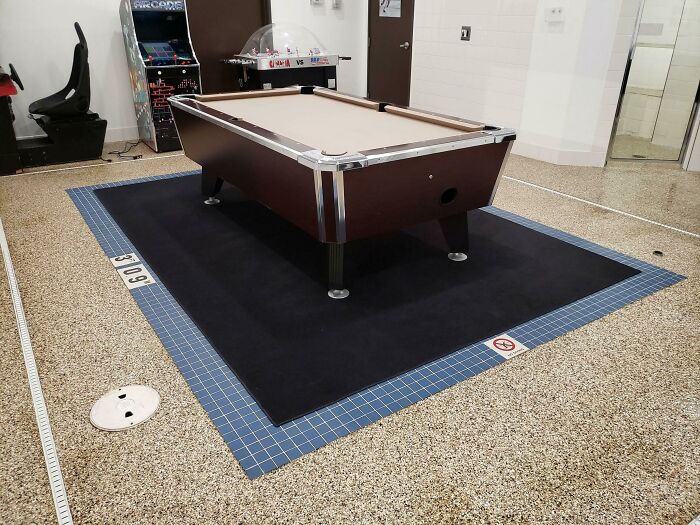 Pool table awkwardly placed in a public space, highlighting unfortunate interior design choices.