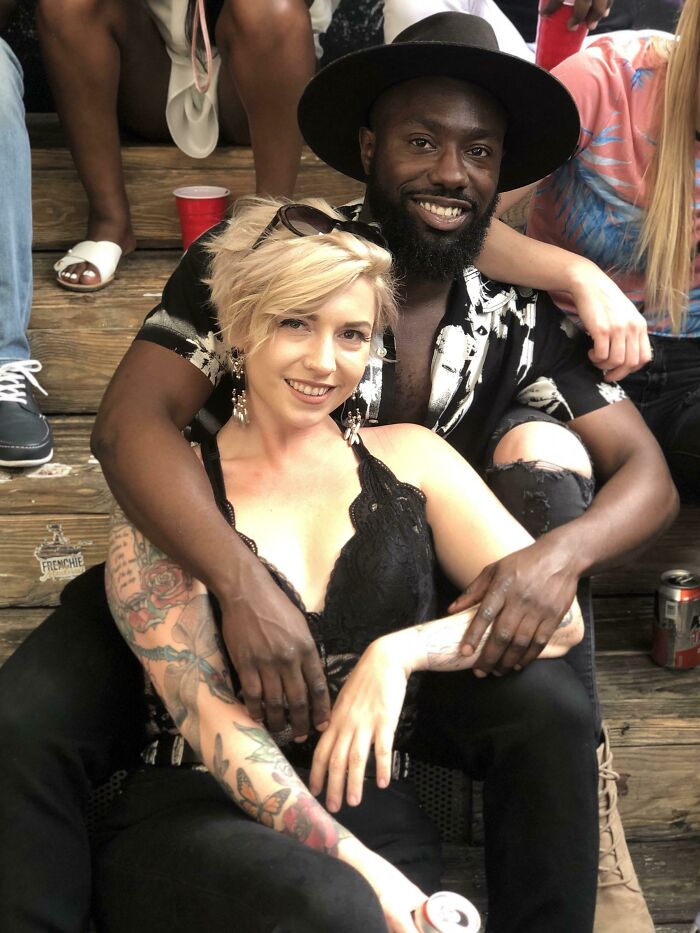A couple embracing on wooden steps during a casual outdoor gathering, showcasing the enduring power of love.