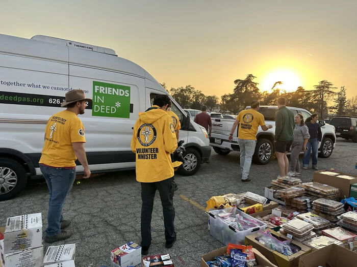 Volunteers organize supplies for nature disaster resilience, with a van in the background and a sunset sky.
