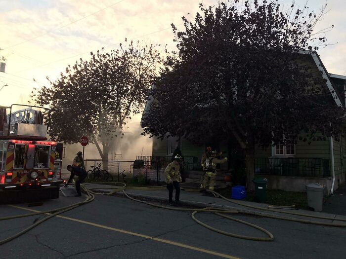 Firefighters responding to a house fire, showcasing nature-disaster-resilience efforts in an urban neighborhood.