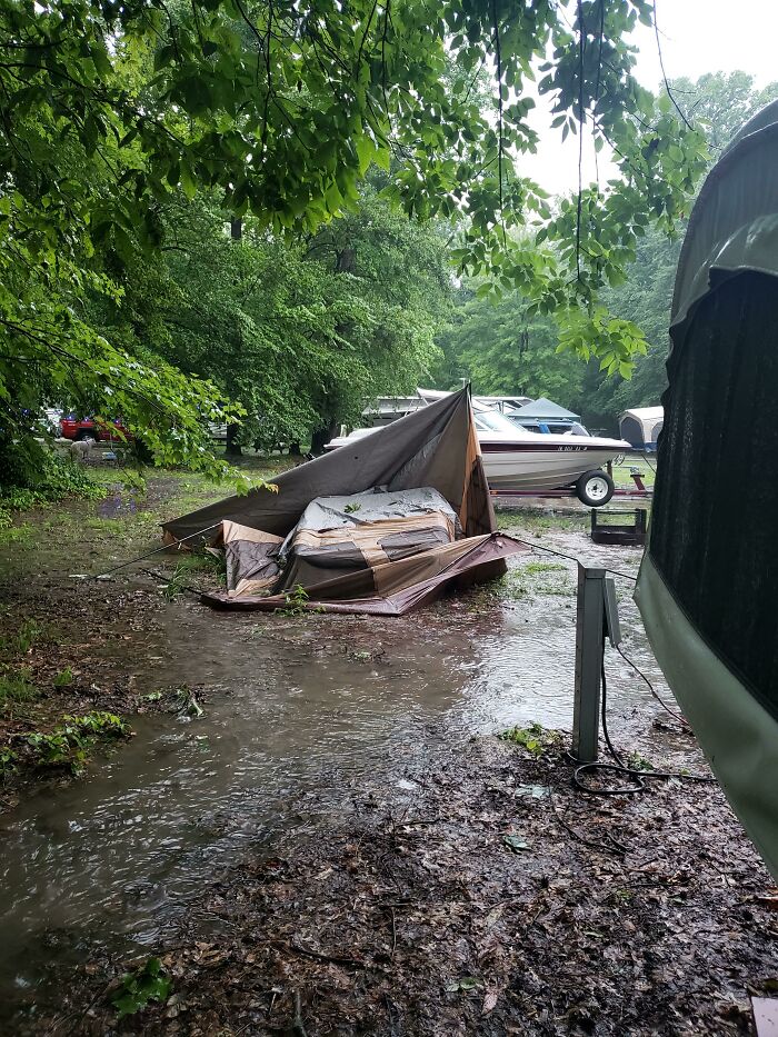 Flooded campsite with collapsed tent and boats, highlighting nature disaster resilience.
