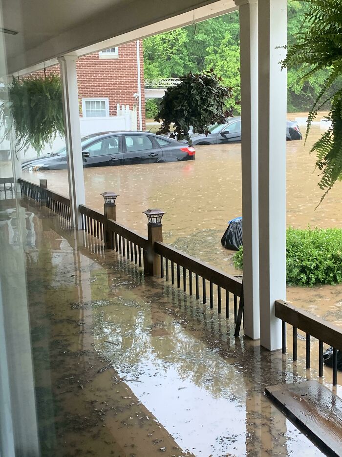 Flooded porch with submerged cars in the background, depicting nature-disaster-resilience challenges.