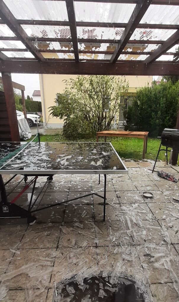 Hailstorm damage on glass table under pergola showcases nature-disaster-resilience.