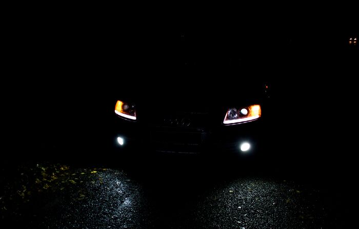 Car headlights in the dark create a pareidolia effect, resembling a face with glowing eyes.