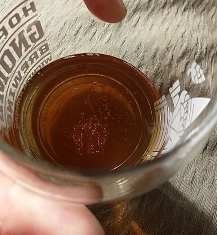 A hand holding a glass of liquid, showing a face pattern on the bottom, illustrating pareidolia-pictures phenomenon.