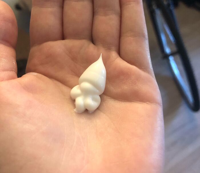 Hand holding a dollop of lotion that resembles a tiny figure, demonstrating pareidolia.