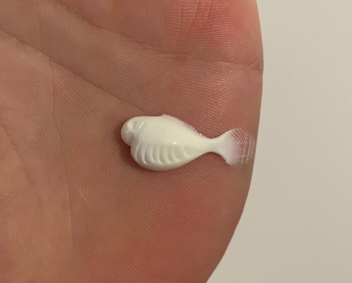 Cream on a fingertip shaped like a fish, illustrating pareidolia.