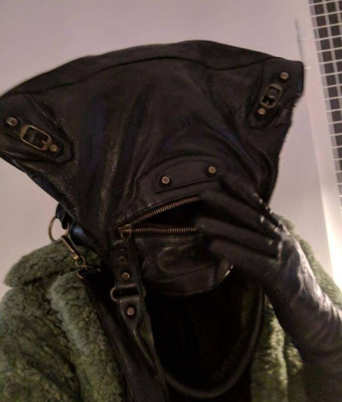 A black leather bag with a zipper resembles a face, demonstrating pareidolia, against a light background.