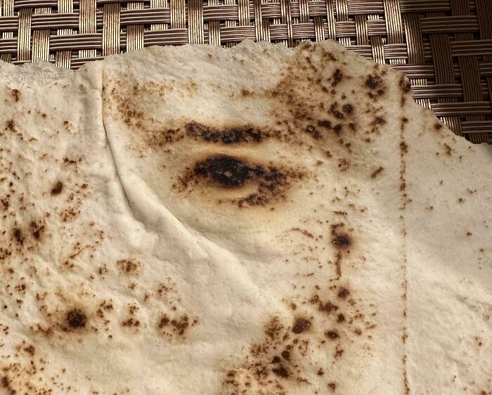 Pareidolia-Pictures: Bread with a burn pattern resembling an eye on a woven basket background.