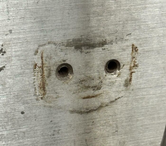 Metal surface with markings resembling a face, illustrating pareidolia.
