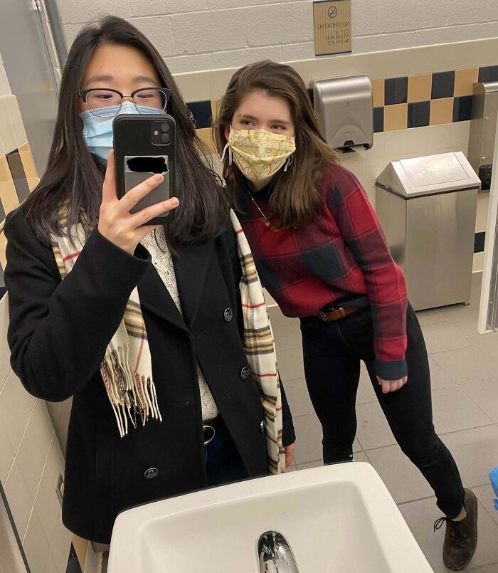 Two people wearing masks take a mirror selfie, showcasing long-distance love.