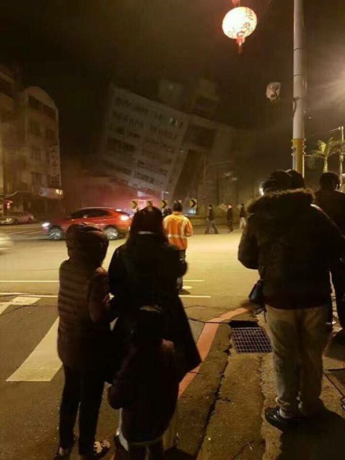 People observing a tilted building after an earthquake at night, highlighting nature-disaster-resilience.