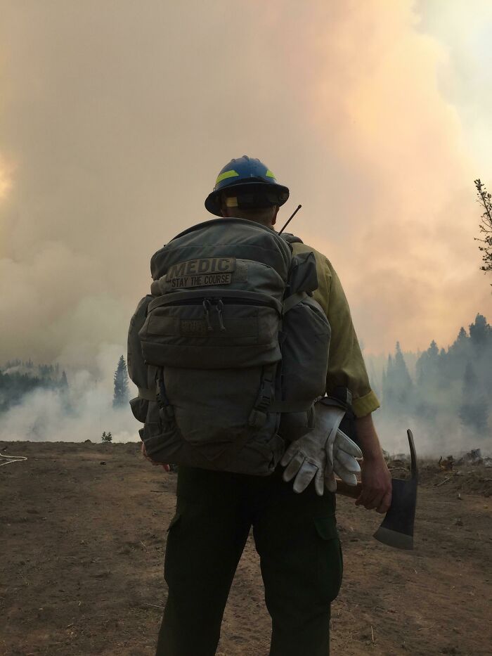 Firefighter with gear stands in smoky forest, highlighting resilience in nature disasters.