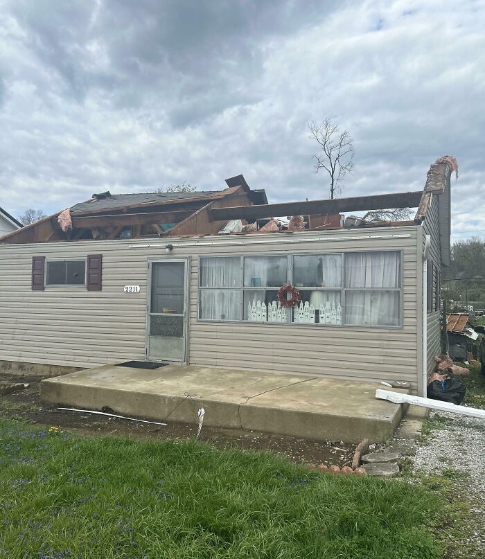 Damaged house with missing roof highlights nature disaster resilience challenges.