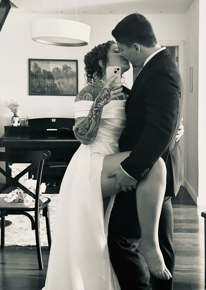 A couple kissing in wedding attire, captured in a mirror selfie, symbolizing long-distance love.