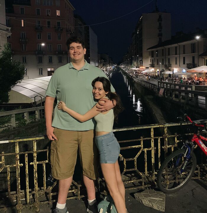 A couple embraces on a bridge at night, showcasing long-distance love.