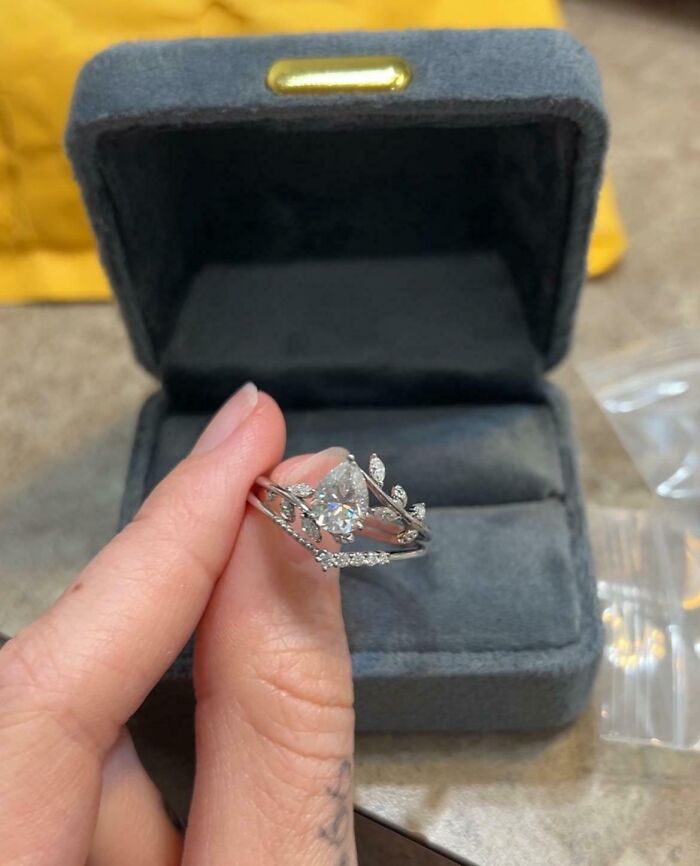 A sparkling engagement ring held in front of an open ring box, symbolizing love wins.