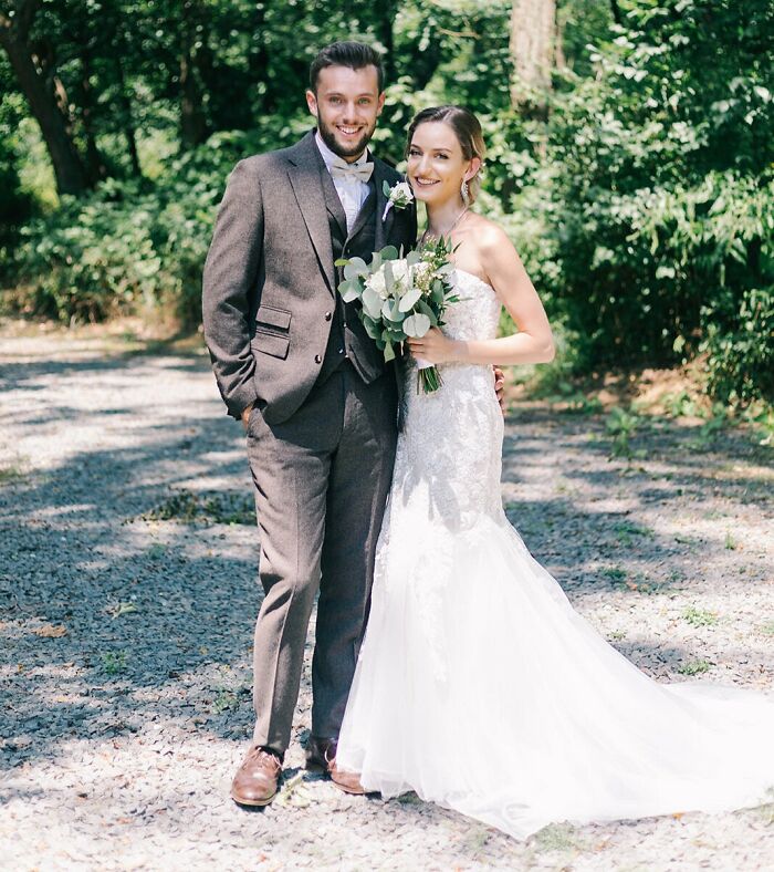A happy couple in wedding attire, embracing outdoors, proving love wins with smiles and elegance.