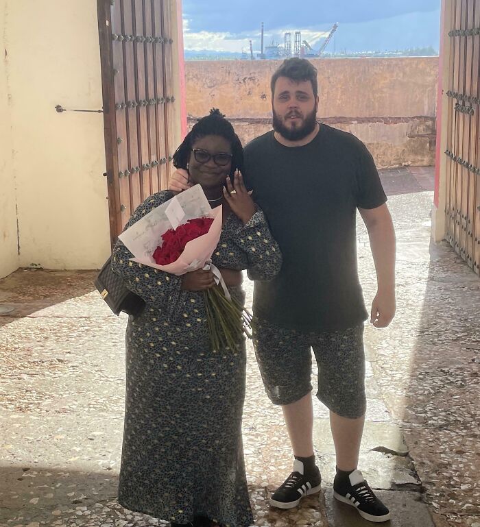 Happy couple in a scenic outdoor setting, celebrating their long-distance love with flowers.