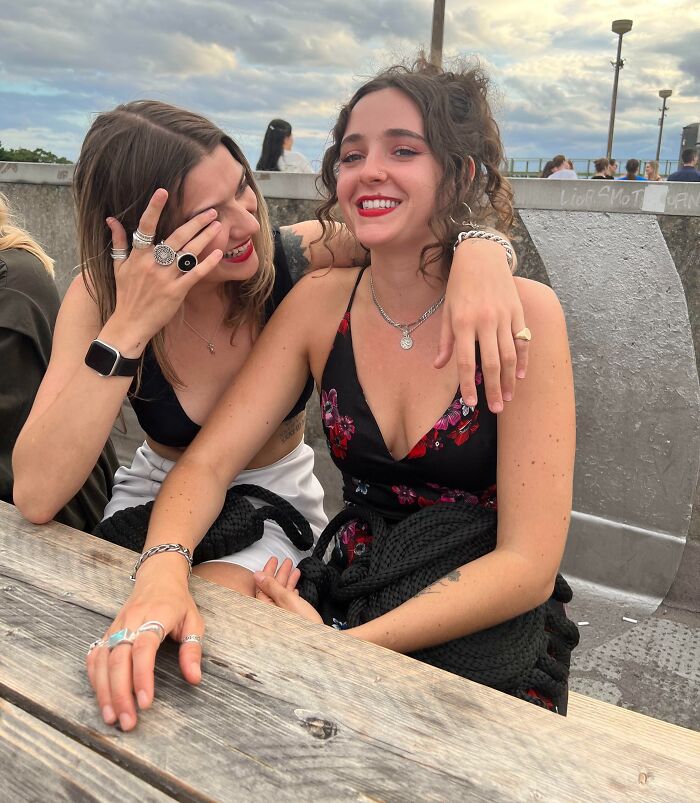 Two women smiling and embracing at a wooden table, showcasing the essence of long-distance love.