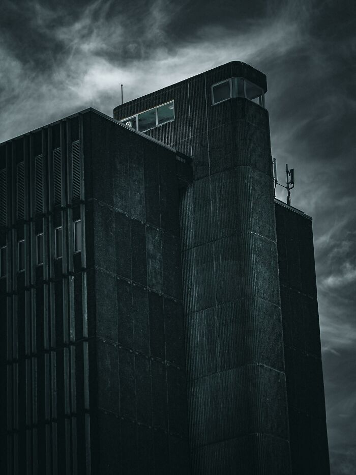 Dark, ominous building with narrow windows and a tower, radiating an evil aura like a supervillain headquarters.