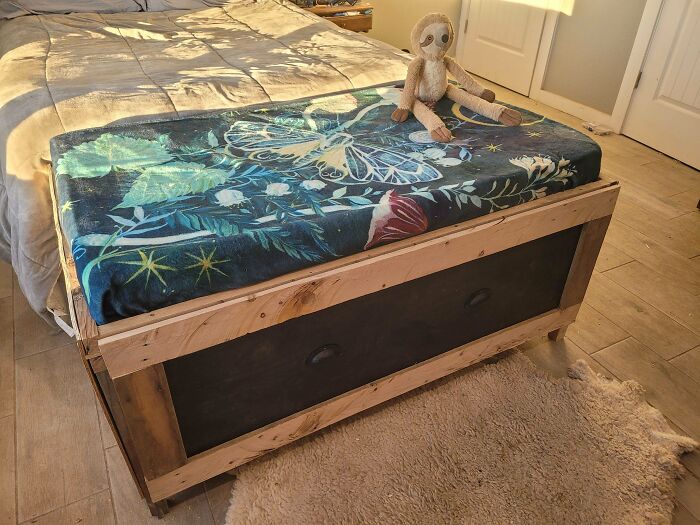 DIY project: wooden bench with butterfly-patterned cushion and stuffed toy, placed at the foot of a bed.