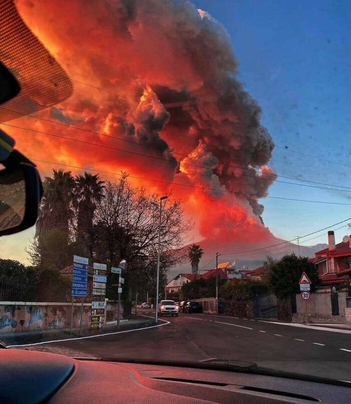 Cloud of ash from volcanic eruption over a suburban road highlights nature-disaster-resilience in the region.