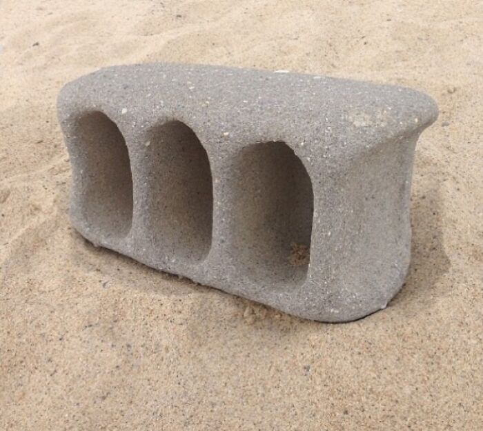 Worn-down concrete block in the sand, illustrating the effects of time.