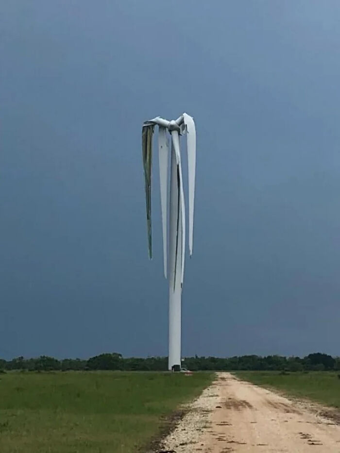 Damaged wind turbine against stormy sky, illustrating nature disaster resilience in renewable energy infrastructure.
