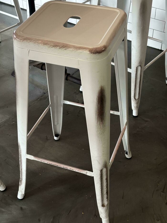 Worn metal stool with visible scratches showing the passage of time.