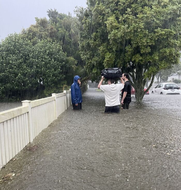 People wading through floodwater, exercising nature disaster resilience in heavy rain.