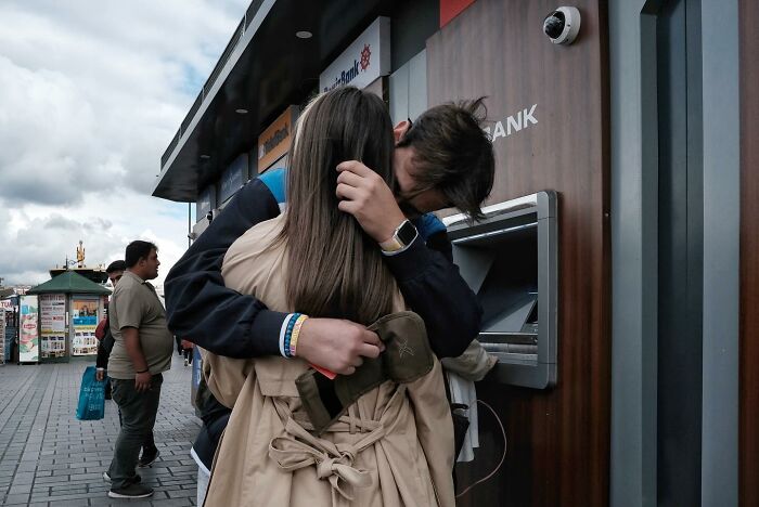 Couple embracing at an ATM, captured accidentally by a street photographer.