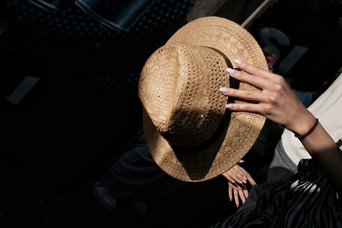 A hand holding a woven hat, casting shadows, accidentally captured by a street photographer.