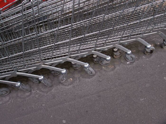 Shopping carts with worn-down wheels in a concrete groove, illustrating how time affects everyday objects.