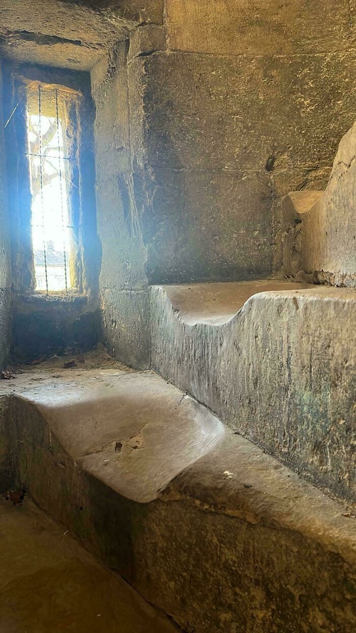 Worn-down stone steps illustrating the passage of time, with a small grated window casting light onto the surface.