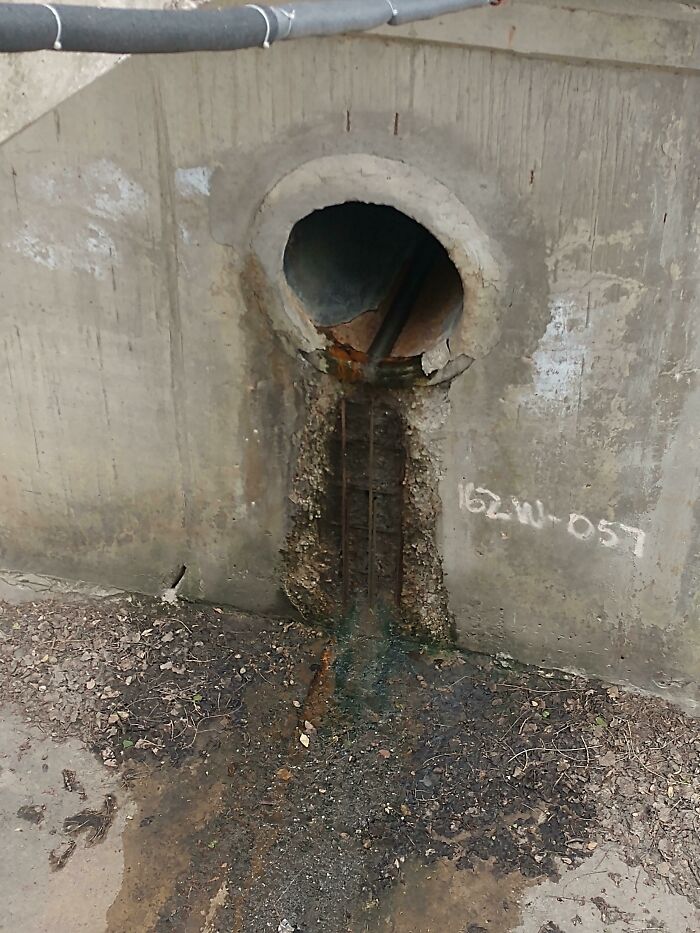 Worn-down concrete pipe with rust stains and exposed rebar, illustrating how time affects structures.