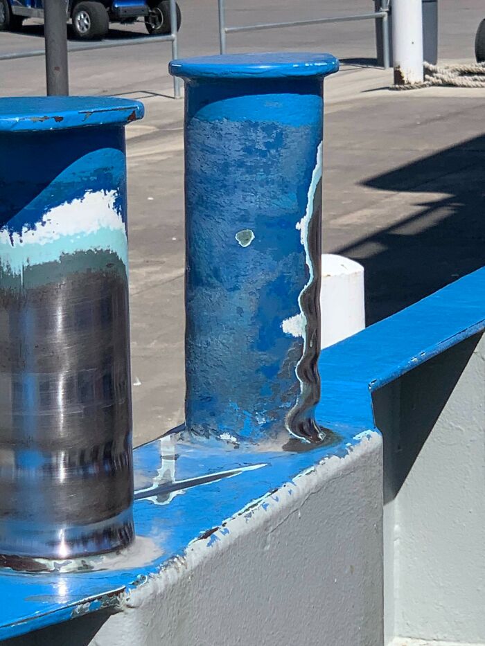 Worn-down blue bollard with peeling paint, illustrating the effects of time and weather.