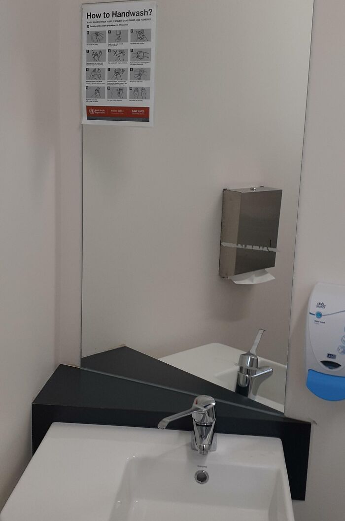 Mirror shows a handwashing sign that's hard to see, illustrating unfortunate public interior designs.