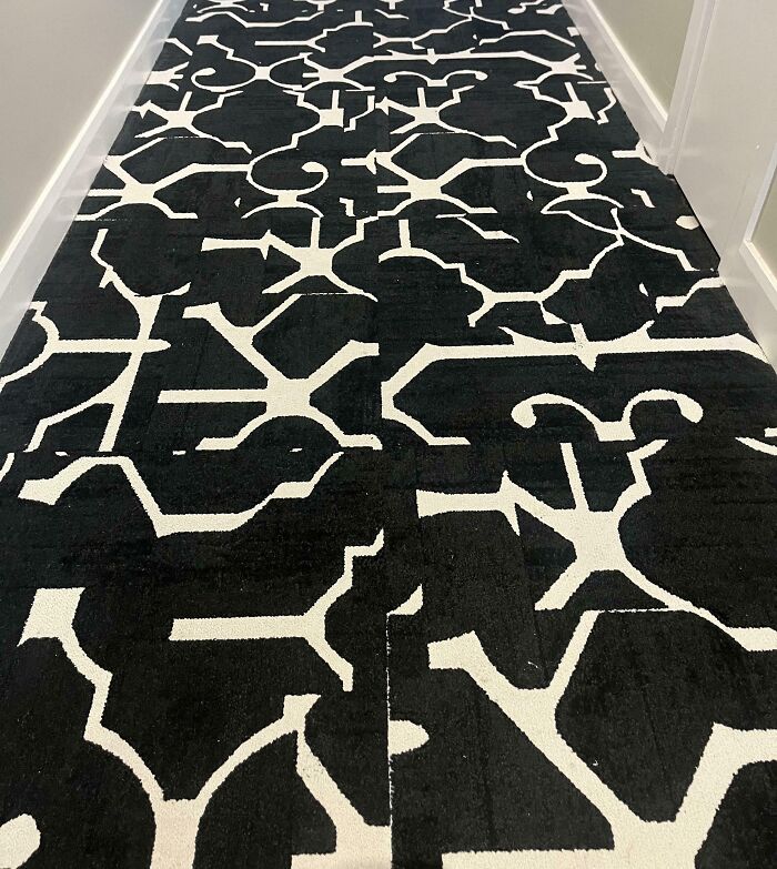 Confusing black and white carpet pattern in a hallway, showcasing unfortunate interior design.